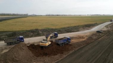 Kırsal bölgedeki çöp kamyonuna toprak yükleyen büyük bir kazıcı