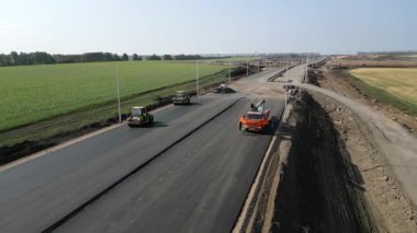 İşçiler ve makineler kırsal alanda yeni bir asfalt otoyol inşa ediyorlar.