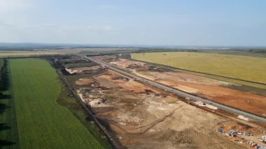 Yeşillik tarım alanlarından geçen yol yapımına geniş çaplı hava manzarası, kırsal bir ortamda altyapı gelişimini gösteriyor