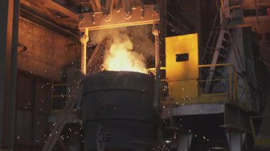 Turuncu erimiş metal, çelik fabrikasında dev bir kepçeye dökülüyor.
