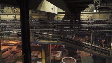 Otomatik makineler çelik fabrikasının içindeki taşıyıcı bant boyunca malzemeleri hareket ettiriyor.