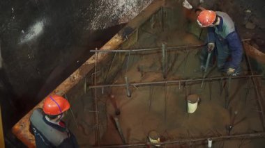 İnşaat işçileri inşaat sahasına beton döküyorlar.