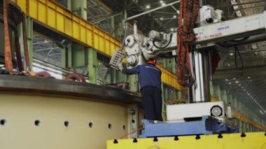 Bir fabrikada, özel makineler kullanan bir işçiyle birlikte metal işleme süreci.