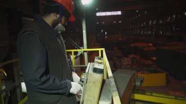 Fabrika işçisi makineleri çalıştırıyor, erimiş metali kalıba döküyor.