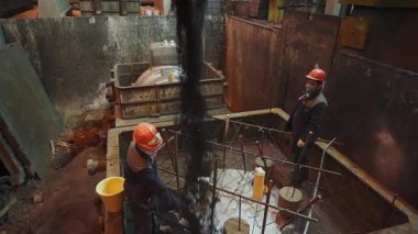 İnşaat işçileri inşaata beton karışımı döküyorlar.