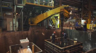 Metalürji işçileri dökümhaneye erimiş metal döküyorlar.