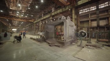 Mühendisler sanayi fabrikasındaki büyük metal kalıplarını inceliyorlar.