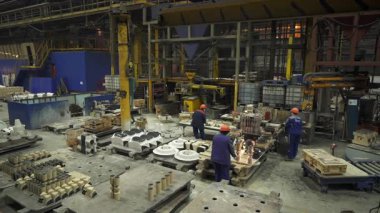 Dökümhane işçileri yoğun endüstriyel ortamda erimiş metali kalıplara dikkatlice döküyorlar.