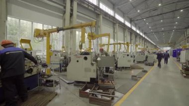 Torna makinesi çalıştıran fabrika işçisi yoğun bir endüstriyel ortamda metal parçaları üretiyor.