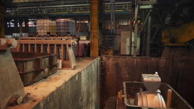 Dökümhanede endüstriyel robotik koldan erimiş metal kalıba dökülüyor