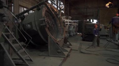 Dökümhane işçileri metal döküm yapıyor, endüstriyel ortamda erimiş metalleri kalıplara döküyorlar.
