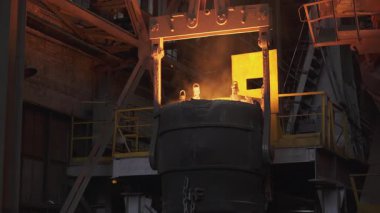 Endüstriyel vinç çelik fabrikasındaki konteynıra erimiş metal döküyor.