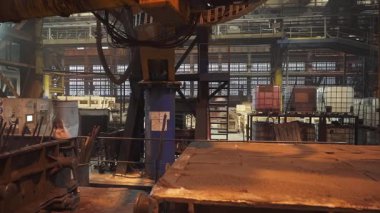 Bir fabrika ortamında metal levhaları tutan ağır makineler.