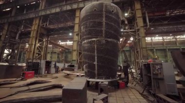 Mühendisler bir fabrikanın içinde büyük metal bir yapı üzerinde çalışıyorlar.