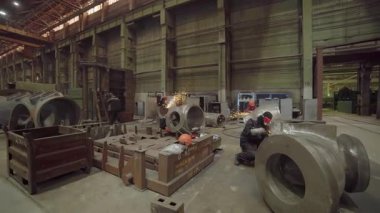 Metal bileşenleri öğüten, endüstriyel üretim süreçlerini sergileyen fabrika işçileri.