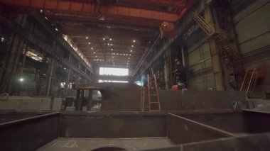 Endüstriyel işçiler büyük bir fabrikada metal parçaları üretiyorlar.