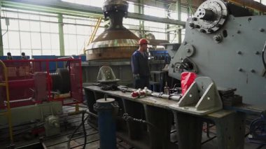 Endüstriyel mühendis, büyük bir fabrika ortamındaki ağır makineleri izliyor.