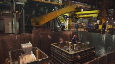 Dökümhane işçileri metal döküm için bir kalıp hazırlıyorlar. Endüstriyel imalatta güvenliği ve hassasiyeti sağlıyorlar.