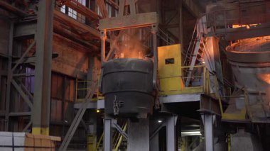 Erimiş metal, çelik fabrikasındaki büyük bir konteynırdan başka bir konteynere dökülüyor.