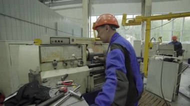 Metal parçası üretmek için torna makinesi kullanan fabrika işçisi.