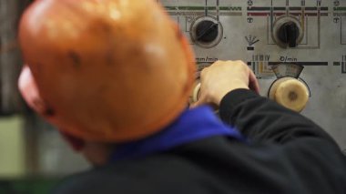 Endüstri işçisi kontrol panelinin düğmelerini ayarlıyor.