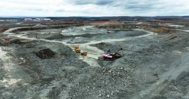 Büyük bir kazıcı maden ocağındaki çöp kamyonlarına cevher yüklüyor