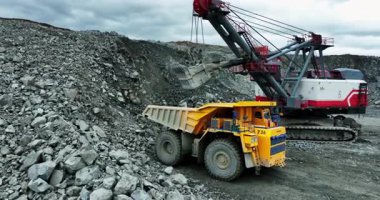 Büyük kazıcı sarı maden kamyonuna cevher yüklüyor.