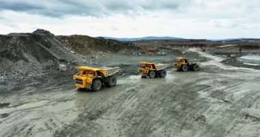 Büyük maden kamyonları açık bir madende çalışıyor, mineraller taşıyorlar.