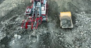Büyük kazıcı taş ocağındaki çöp kamyonuna taş yüklüyor.