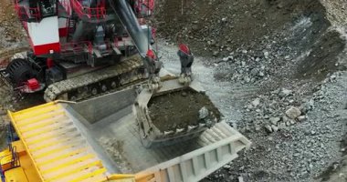 Büyük kazıcı madencilik alanındaki çöp kamyonuna taş ve kir döküyor.