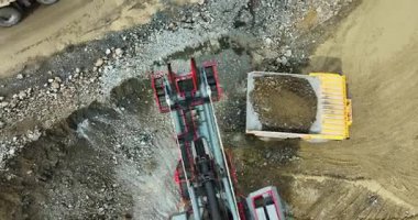 Büyük kazıcı, maden sahasındaki çöp kamyonuna kaya ve toprak yüklüyor.