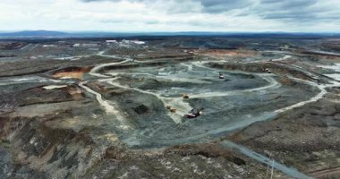 Taş ocağı kamyonları büyük bir açık maden ocağında toprak malzemelerini yükleyip taşıyorlar.