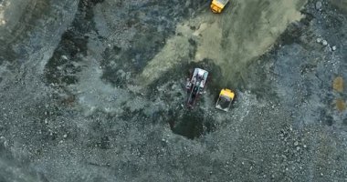 Eklemli nakliye kamyonu taş ocağındaki çukura çakıl boşaltıyor.