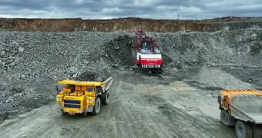 Excavator loading rocks into mining truck in open pit quarry