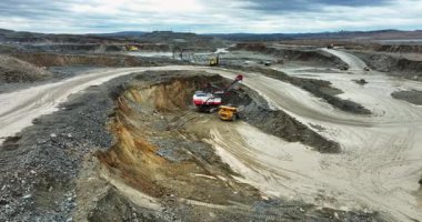 Büyük kazıcı maden ocağındaki çöp kamyonuna cevher yüklüyor.