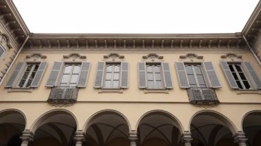 Kemerli sütunlar ve gri panjurlar içeren bir binanın mimari ayrıntıları