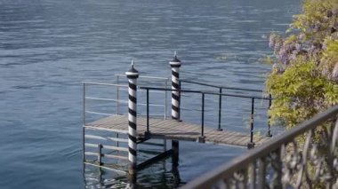 Huzurlu göl manzarasında siyah ve beyaz direkleri olan küçük, büyüleyici bir ahşap iskele var.