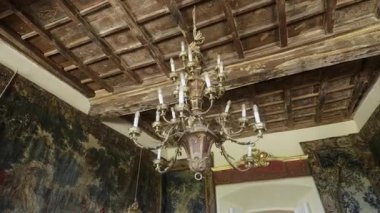 Süslü avize bir odayı duvar halısı ve ahşap tavanla aydınlatır.