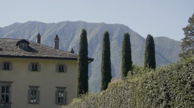 İtalyan Alpleri 'nde selvi ağaçları ve çitlerle çevrili lüks bir villanın manzarası.