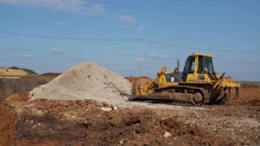 Sarı buldozer inşaat alanında çalışıyor, çakıl taşıyor. Kırp