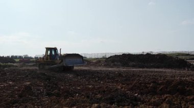 Sarı buldozer inşaat alanında toprak taşıyor. Kırp