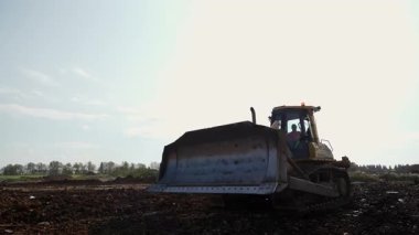 Buldozer büyük bir inşaat sahasına toprak atıyor. Kırp