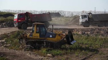 Sırbistan 'ın Vrsac kenti - Haziran 2025: İnşaat sahasında çalışan buldozer, toprak ve molozları hareket ettirirken, çöp kamyonları da malzeme taşıyor. Kırp