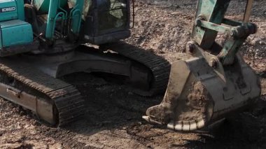 Yeşil kazıcı bir inşaat alanında toprağı kazıyor ve hareket ettiriyor. Kırp
