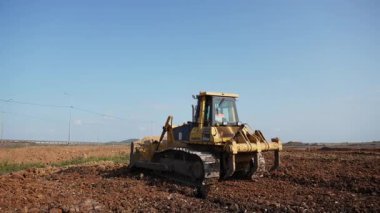 Sarı buldozer inşaat sahasında zemini düzleştiriyor. Kırp