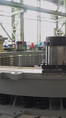 Fabrika işçisi büyük dairesel bir endüstriyel bölümü inceliyor ve notlar alıyor.