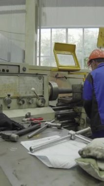 Torna makinesi çalıştıran fabrika işçisi, metal parçaları üretiyor.