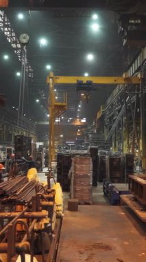 Endüstriyel işçiler geceleri büyük bir fabrikada beton ürünler üretiyorlar.