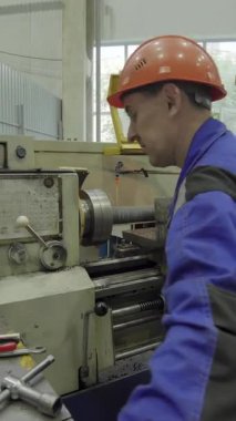 Metal parçası üretmek için torna makinesi kullanan fabrika işçisi.