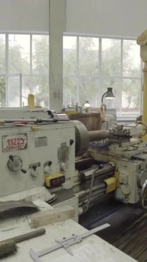 Torna makinesi işleten yetenekli bir fabrika işçisi, işlek bir fabrikada metal parçaları üretiyor.